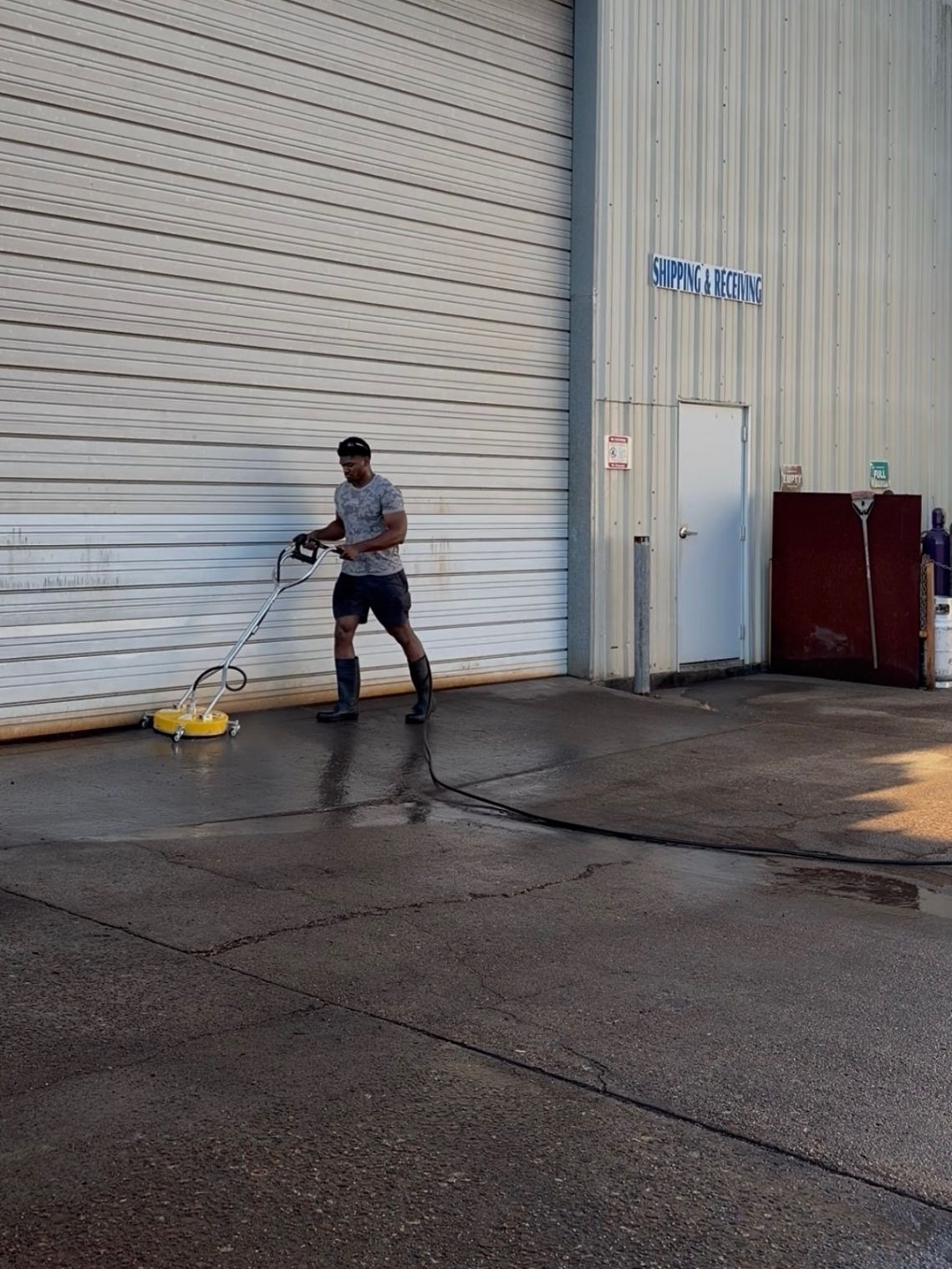 Texas Muscle Wash owner cleaning the concrete at an industrial loading dock with a surface cleaner